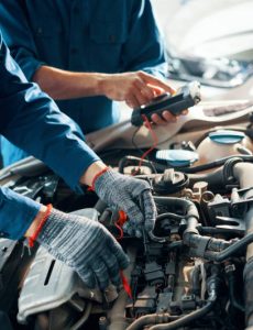 Hands of professional mechanics using professional tool for testing car motor in garage